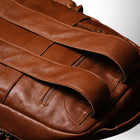 Un gros plan d'un magnifique sac à dos en cuir brun. On peut voir une des bretelles, des coutures et des fermetures éclair.
— vue 4
