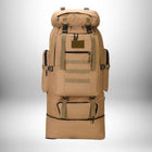 Un grand sac à dos beige de style militaire est assis à quatre-vingt-dix degrés contre un fond dégradé. Les sacs à dos ont beaucoup de compartiments extérieurs, de fermetures éclair et de sangles. Un sac isotherme intégré semble être au bas du sac de randonnée.
— vue 8