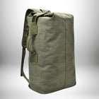 Un sac de sport en toile vert olive, avec des bretelles et des poignées de transport. Le sac est en position verticale avec le rabat supérieur replié et attaché. Il est placé devant un dégradé de fond gris clair. — vue 8