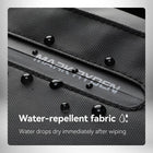 Gros plan sur un tissu noir d'un sac a dos semi rigide avec des gouttes d'eau dessus et un texte indiquant "Water-repellent fabric: water drops dry immediately after wiping". — vue 5