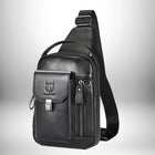 Un sac de poitrine noir en cuir posé sur un fond blanc et gris. Le sac a une sangle noire unique avec une boucle argentée qui est posée sur l'épaule. Il y a une petite poche avec une boucle argentée sur le devant avec l'emblème du taureau estampé. Il y a également une poche zippée et une poignée sur le dessus. — vue 7