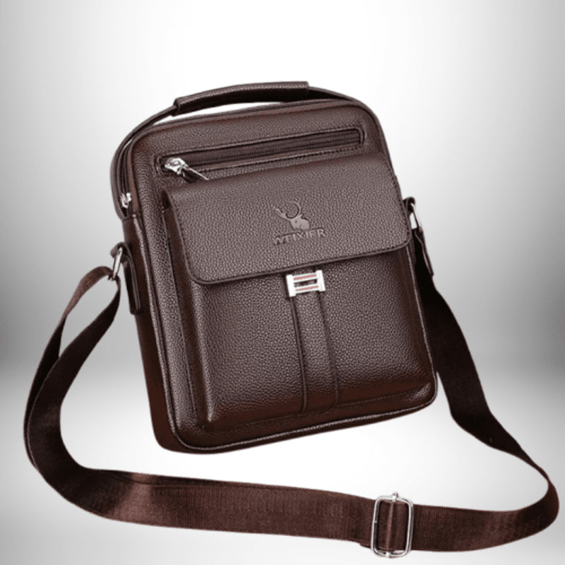 Un sac à bandoulière en cuir brun, avec une poignée en haut. Le devant présente une poche avec un rabat et une petite poche zippée. Le sac porte le logo "WEIXIER" sur le rabat.