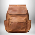 Gros plan d'un sac à dos camel en cuir à l'aspect vintage. Le sac à dos est de couleur marron clair avec une poche avant plus petite, des poches latérales et un rabat sur le dessus — vue 2