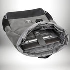 A close-up shot of a modern backpack, opened to reveal a laptop and tablet securely held inside. The backpack is gray with black accents, boasting a sleek design. The interior features a dedicated compartment for electronics, secured by a strap. The open flap of the backpack showcases a minimalist, functional design, perfect for holding a laptop or tablet. — vue 6