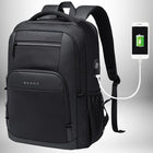 Un sac à dos noir en tissu et simili cuir, avec une inscription « BANGE » en lettres blanches sur la poche frontale. Il possède une poche latérale en filet et un port USB pour le chargement. Le sac à dos est relié à un téléphone portable blanc en charge. L'écran du téléphone affiche une batterie verte en charge.
— vue 1