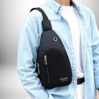 Un homme porte un sac banane bandouliere homme noir. L'homme porte une chemise bleue claire boutonnée et une chemise blanche en dessous. Le sac est porté sur son épaule droite et autour de son torse, avec une poche avant zippée. Le sac porte une étiquette avec l'inscription "Mode" et un bouton en métal.
— vue 5