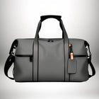 Un sac de sport gris avec des poignées noires, une bandoulière et une étiquette. Le sac a une poche zippée noire et une garniture noire. — vue 3