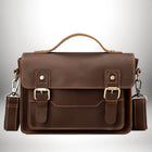 Gros plan d'un cartable homme moderne en cuir marrron avec bandoulière. Le sac a une poignée et deux boucles métalliques pour fermer. — vue 8