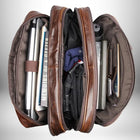 Vue de dessus d'une sacoche medecin en cuir marron ouverte, remplie d'objets tels qu'un ordinateur portable, des livres, des vêtements et des accessoires électroniques.
— vue 6