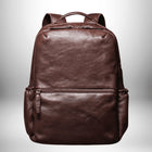 Un sac à dos marron en cuir avec une poche zippée en bas. Il est en forme rectangulaire et a une poignée en haut.
— vue 7