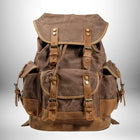 Un sac à dos en toile marron rustique avec des sangles et boucles en cuir.
— vue 1