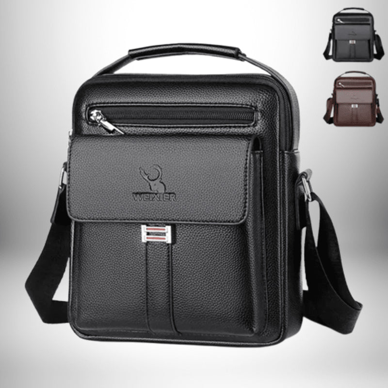 Un sac à main en cuir noir pour homme avec une poche avant et une sangle d'épaule. Il y a également une petite poignée en haut. En arrière-plan, il y a deux autres couleurs de sacs disponibles : gris et brun.
