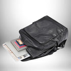 Un sac à dos en cuir noir est posé sur le côté. À l'intérieur du sac à dos, on peut voir un ordinateur portable, un téléphone, un bloc-notes et un livre. Le sac à dos est contre un arrière-plan blanc dégradé vers le gris. — vue 5