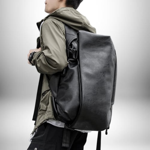 Une personne portant un sac à dos en cuir noir pleine longueur. La personne porte un manteau kaki sur le dos et des pantalons cargo noirs.