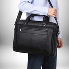 Une personne porte un sac noir sur son épaule. La personne porte une chemise bleue et un jean bleu. Le sac a une fermeture à glissière sur le devant.
 — vue 5
