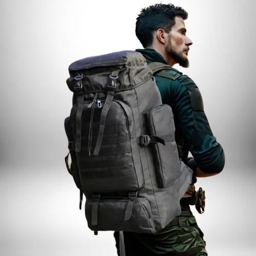 Un homme portant un sac à dos volumineux regarde sur le côté, l'arrière-plan est flou et blanc.
