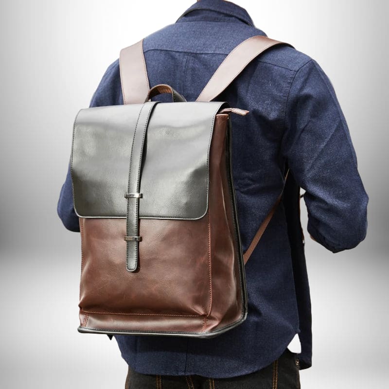 Vue arrière d'un homme portant un sac à dos urbain homme,sac à dos urbain en cuir marron foncé et noir. Le sac à dos est attaché à l'homme, et la personne porte une chemise ou une chemise à manches longues et un jean. L'arrière-plan est flou et d'une couleur de dégradé. 