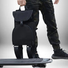 Gros plan d'une personne tenant un sac à dos porte skate, un sac à dos noir avec des sangles pour attacher un skateboard. — vue 5