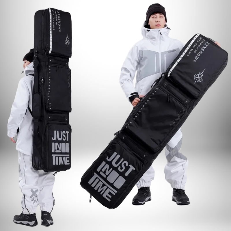 Deux personnes portant un sac à dos snowboard noir. Le sac est long et rectangulaire, avec plusieurs compartiments et le texte "JUST IN TIME" en gros caractères. Les personnes portent des vêtements de neige blancs.