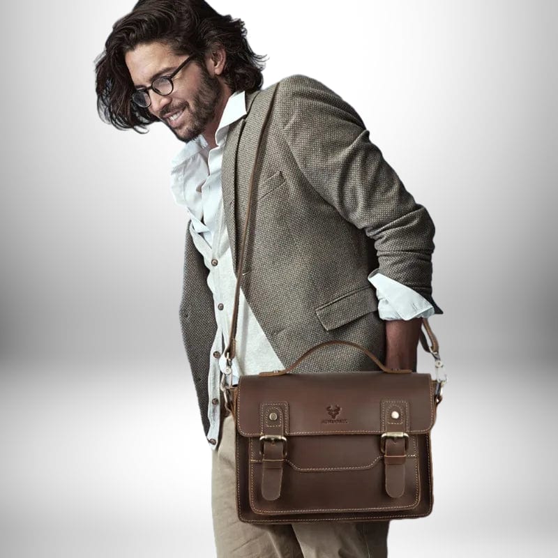 Un homme élégant porte un cartable homme moderne en cuir marron, associé à une veste de costume et des lunettes.