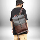 Un homme vu de dos porte un sac à dos urbain homme,sac à dos urbain en cuir marron et noir. Il porte un chapeau noir, un masque noir et un tee-shirt noir et un pantalon beige. — vue 4