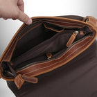 Gros plan d'un sac bandoulière homme cuir marron ouvert qui révèle plusieurs compartiments. Une main est visible en train d'ouvrir le sac. — vue 5