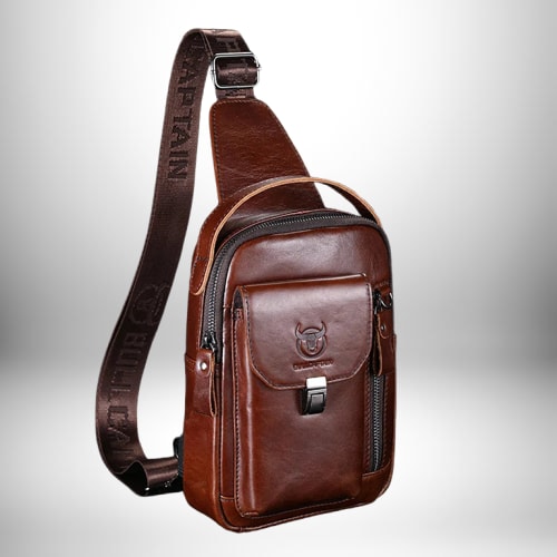 Un sac à bandoulière en cuir marron avec une bandoulière brodée de texte, avec des fermetures à glissière et une petite poche.