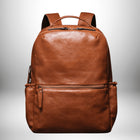 Un sac à dos en cuir marron avec une poignée sur le dessus ainsi que deux bretelles et deux poches zippées. — vue 1