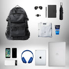 L'image montre un assortiment d'articles personnels, dont un sac à dos ergonomique noir, des lunettes de soleil, une montre, un stylo, un ordinateur portable, un parapluie, un cahier, un t-shirt blanc, un produit pour le visage, un téléphone, des écouteurs, une tablette, et une batterie externe, posés sur un fond dégradé. — vue 5