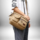 Une personne portant un sac de ville homme en toile beige avec plusieurs poches et une bandoulière.
 — vue 3