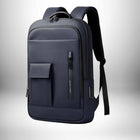 Voici un sac a dos homme design de couleur bleu foncé, placé sur un fond blanc et une ombre dégradée. Le sac à dos a une poche sur le devant, une poche zippée verticale, et une poignée sur le dessus. Les bretelles noires se trouvent sur le haut du sac.
 — vue 1