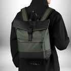 Une photo prise d'un homme de dos qui porte un sac à dos business,sac a dos business noir et vert. Le sac à dos est de conception moderne et comprend une section noire sur le dessus et le bas ainsi que des bretelles noires et vertes et une attache bouclée. — vue 4