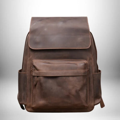 Gros plan d'un sac à dos camel​ en cuir avec une fermeture par rabat et une poche à fermeture éclair.