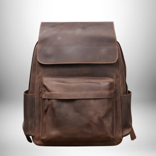 Gros plan d'un sac à dos camel​ en cuir avec une fermeture par rabat et une poche à fermeture éclair.