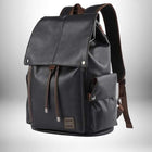 A black backpack with a flap closure, brown accents, and a patch; the backpack features a spacious main compartment, a front pocket, and shoulder straps; this is a stylish and functional backpack — vue 1