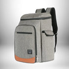 Un sac à dos picnic gris avec des accents bruns et noirs. Le sac à dos a plusieurs poches et une silhouette carrée, ce qui suggère qu'il est conçu pour transporter des articles de pique-nique. — vue 1
