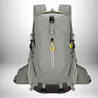 A gray hiking backpack with yellow accents. The backpack has a front zip pocket, mesh side pockets and multiple straps. The backpack is centered and in the foreground, against a gradient white background. — vue 1