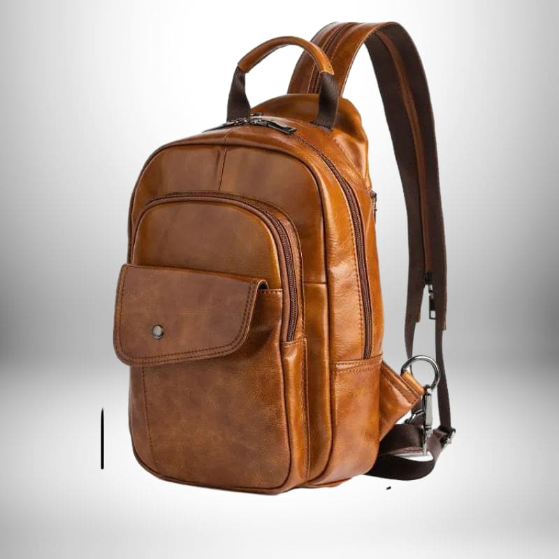 Un mini sac à dos homme cuir marron, avec une poche avant et une poignée supérieure.