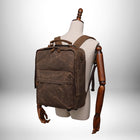 Un sac à dos marron foncé sur un mannequin. Le sac à dos semble être en toile cirée. Le style est vintage et peut être utilisé comme bagage a main easy jet. — vue 6
