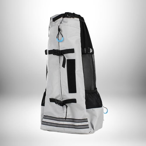 Un sac a dos transport chien de couleur gris avec des bandes réfléchissantes en bas. Un côté est en mesh noir. Le sac dispose de plusieurs sangles et boucles.
