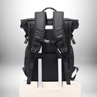 Vue arrière d'un sac à dos homme travail imperméable noir, posé sur une valise. Le sac a des bretelles rembourrées, une poignée et des poches latérales. — vue 5