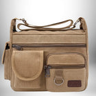 Un sac de ville homme en toile de couleur beige, avec plusieurs poches à fermeture éclair et une bandoulière réglable.
 — vue 1