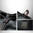 Close-up of a black leather  "bag" with brown drawstrings and a small, rectangular patch that reads "On one's Way, Why ontought to." — vue 5