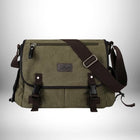 Voici une description de l'image sous forme de texte alternatif :

Un sac bandoulière en toile homme de couleur olive avec des garnitures marron foncé. Le sac est rectangulaire et comporte un compartiment principal, une poche avant et une poche zippée sur le dessus. Il y a deux boucles à l'avant pour fixer le rabat et une bandoulière réglable. Le sac est sur un fond dégradé clair.
 — vue 1