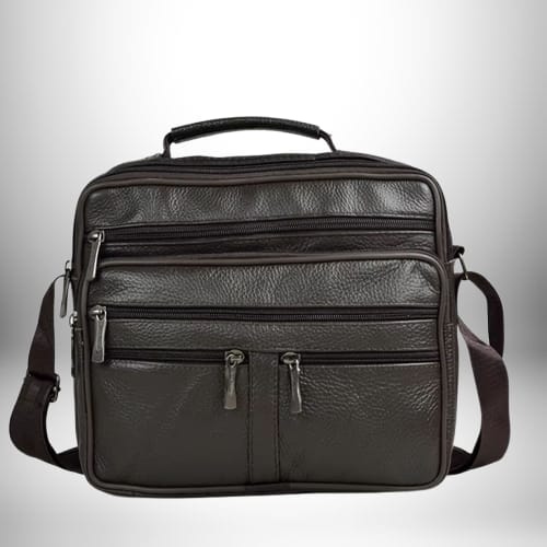 Un sac bandoulière homme cuir souple​ est présenté. Il est de couleur marron foncé avec plusieurs compartiments zippés. Il possède également une poignée sur le dessus et une bandoulière réglable.
