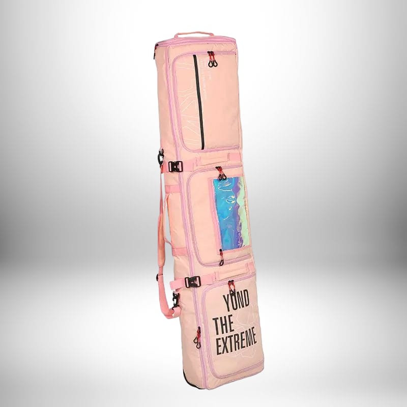 Image d'un sac à dos snowboard rose clair avec des éléments rose plus foncé et une fenêtre en plastique iridescent. Le sac est long et étroit avec plusieurs compartiments. Le texte "Yond The Extreme" est imprimé en bas