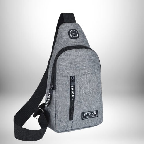 Un sac de sport bandoulière gris avec une poche zippée. Il possède une bandoulière noire et une étiquette "Fashion".
