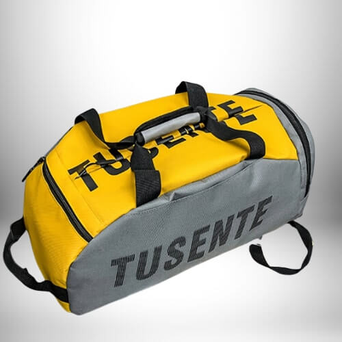 Voici une photo d’un sac à dos de foot avec compartiment chaussure, de couleur jaune vif et gris ardoise. Le nom de la marque, « TUSENTE », est imprimé en lettres grises sur le côté gris du sac.  
