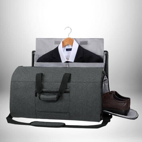 Un sac de voyage convertible gris avec un compartiment pour vêtements suspendus et un compartiment séparé pour chaussures, contenant un costume et des chaussures.