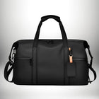 A high-angle shot displays a black duffel bag with two handles at the top, a shoulder strap, and a luggage tag. — vue 1